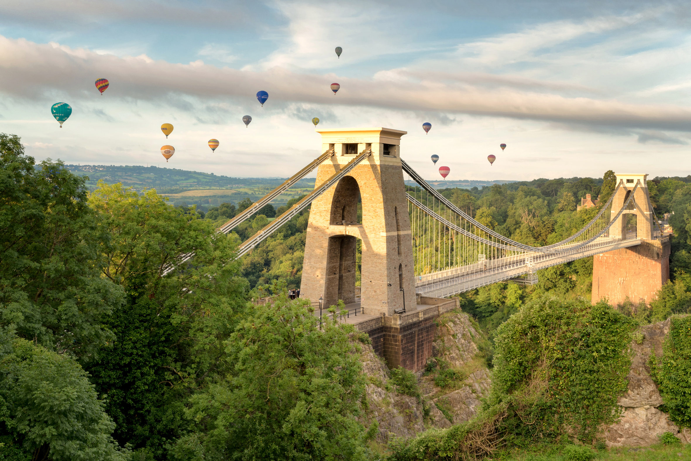 Hot air balloons above a suspension bridge.