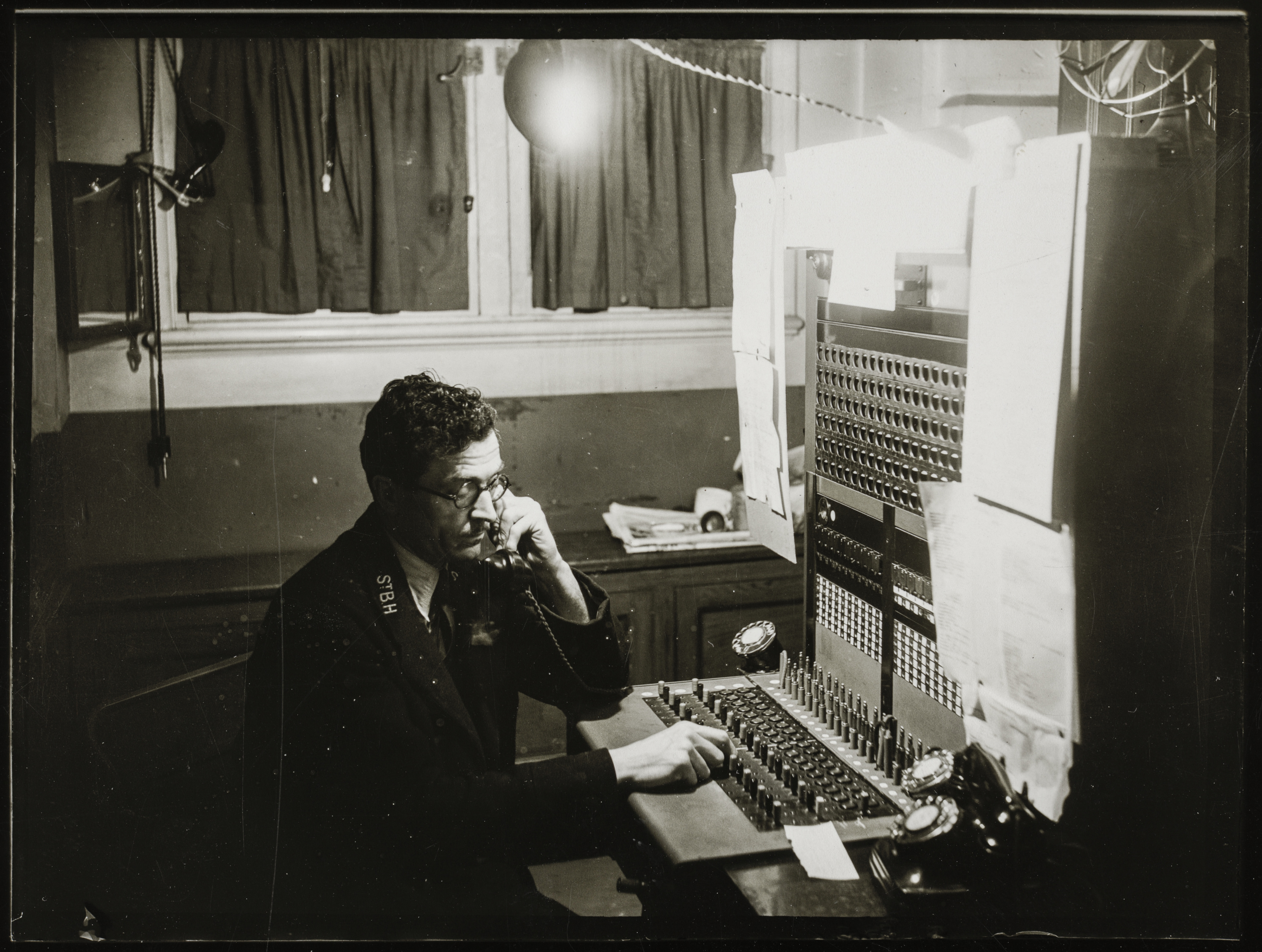 A man operating a 1940s telephone switchboard.