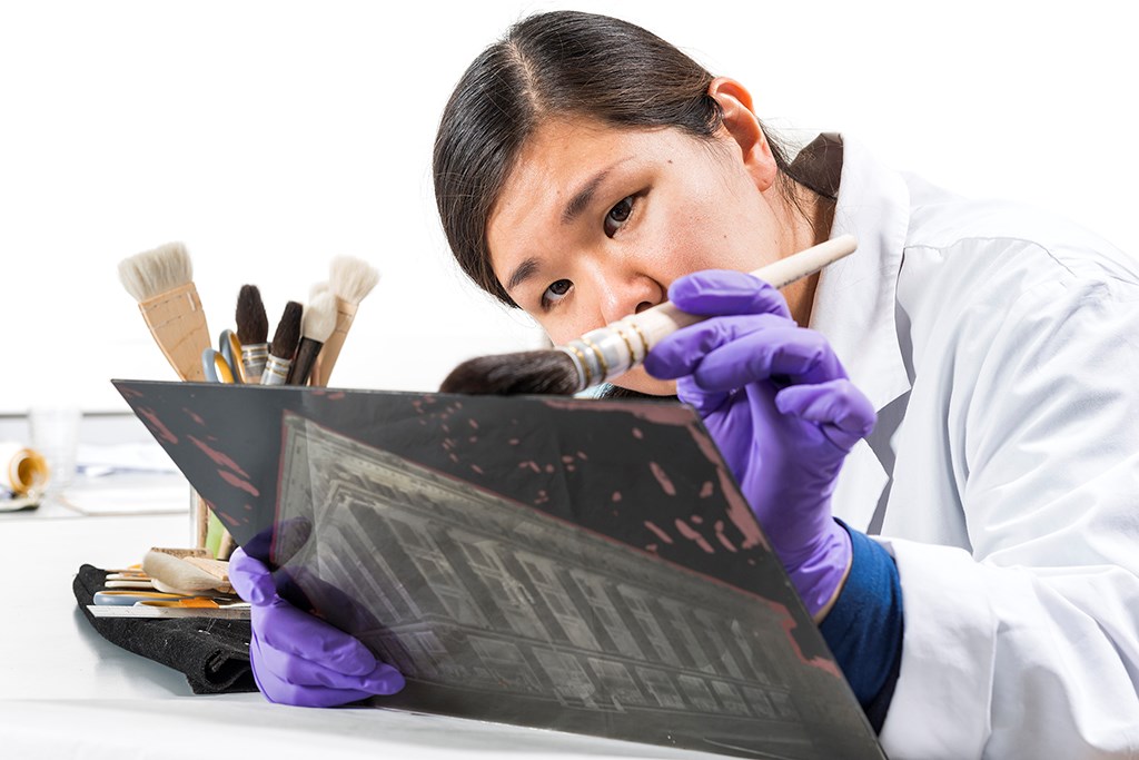 A conservator examining a glass plate negative.